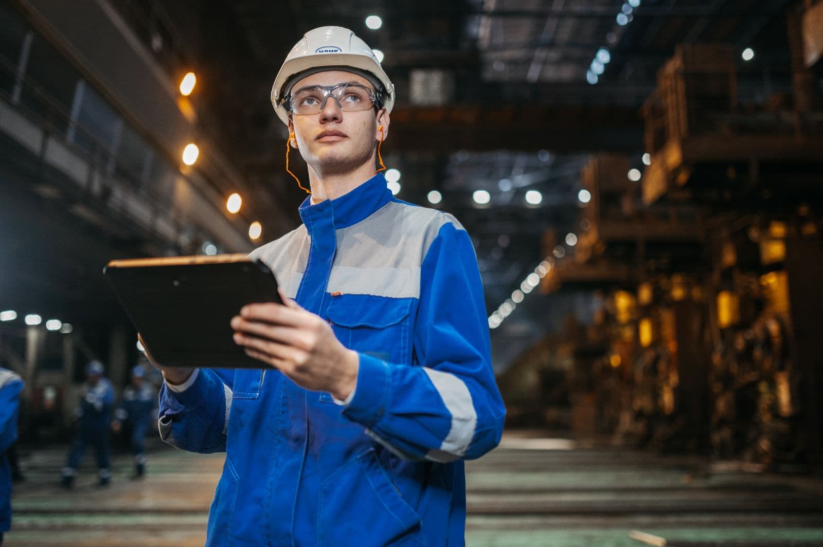 Engenheiro em ambiente industrial analisando informações em um tablet